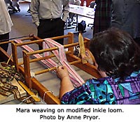 Mara weaving on modified inkle loom. Photo by Anne Pryor.